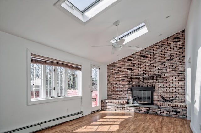 unfurnished living room featuring a brick fireplace, vaulted ceiling with skylight, wood finished floors, a ceiling fan, and a baseboard radiator