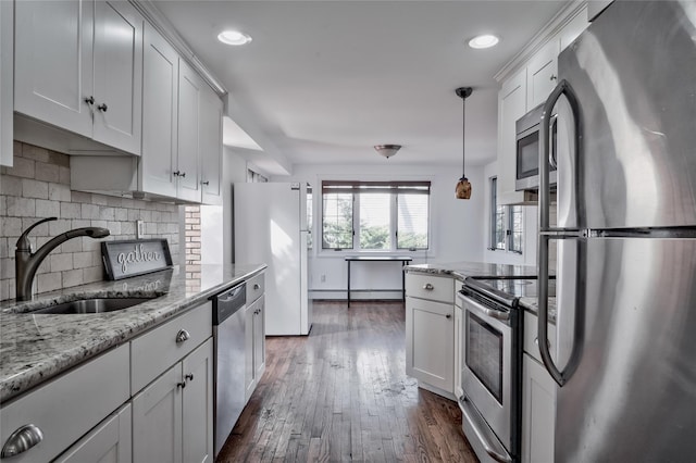 kitchen with a sink, light stone counters, dark wood-style floors, stainless steel appliances, and white cabinets