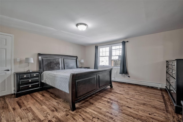 bedroom with a baseboard radiator and wood finished floors