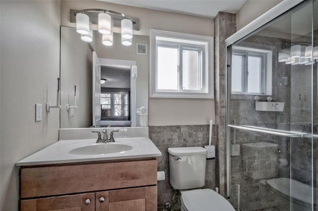 full bathroom featuring vanity, visible vents, a shower stall, tile walls, and toilet