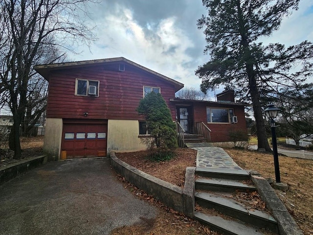 split level home with driveway, a chimney, and a garage