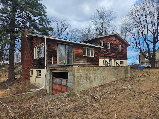 back of property with an attached garage and a chimney