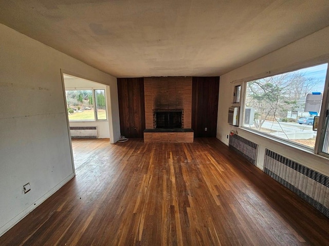 unfurnished living room featuring radiator, a fireplace, and wood-type flooring