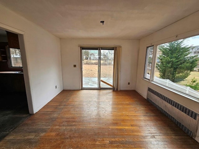 empty room with hardwood / wood-style floors and radiator heating unit