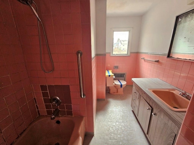 full bath with toilet, tile walls, wainscoting, bathtub / shower combination, and vanity