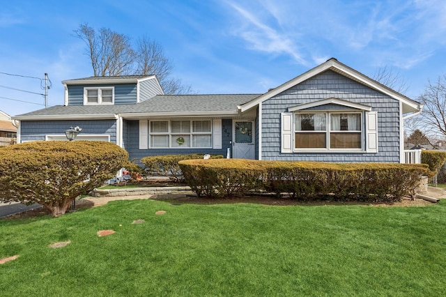 view of front of house with a front yard and a shingled roof