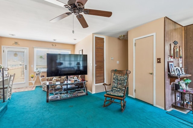 living room featuring carpet flooring, baseboards, and a ceiling fan