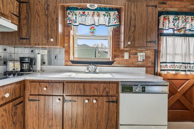 kitchen featuring dishwasher, light countertops, brown cabinets, black electric cooktop, and a sink