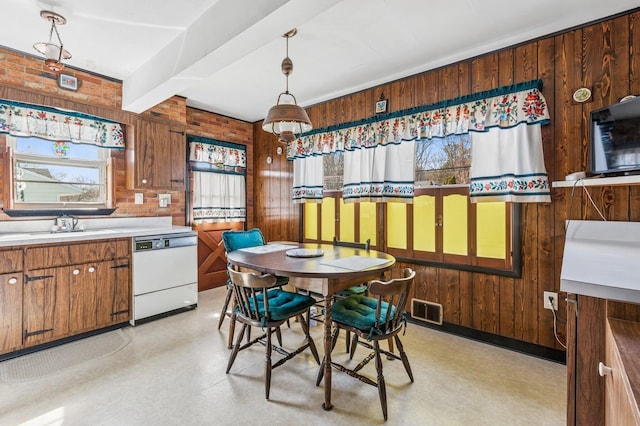 dining space with visible vents, light floors, wooden walls, and beamed ceiling