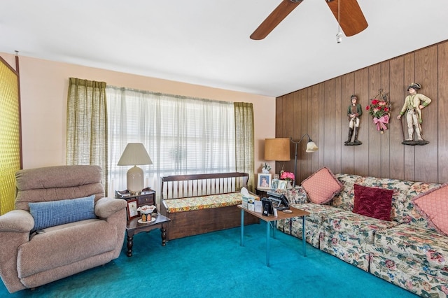 carpeted living room featuring wooden walls and ceiling fan