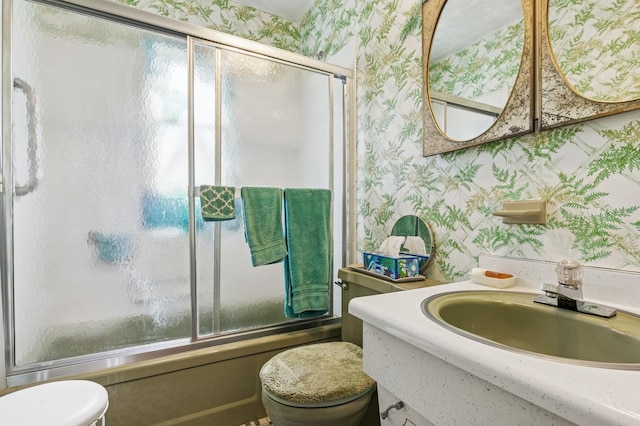 bathroom with vanity, toilet, shower / bath combination with glass door, and wallpapered walls