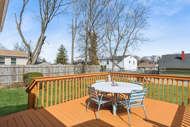 wooden terrace with a residential view, a lawn, a fenced backyard, and outdoor dining space