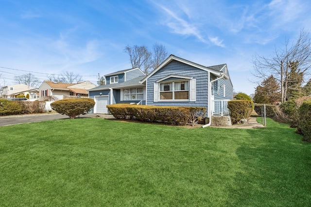 view of front of property featuring a front lawn, an attached garage, fence, and driveway