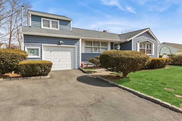 view of front of property featuring a front yard, a chimney, driveway, and a shingled roof