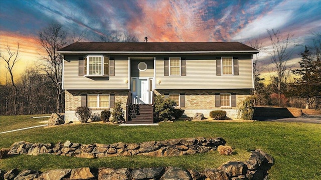 bi-level home featuring brick siding, a front yard, and entry steps