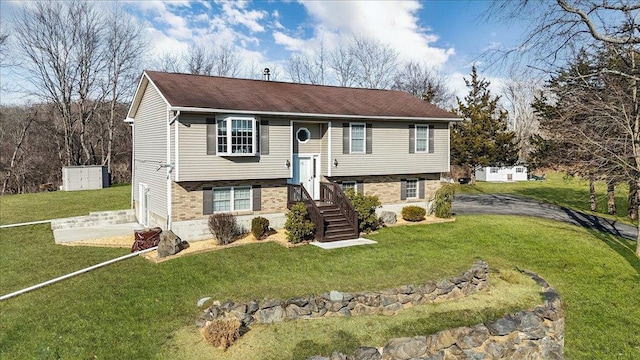 split foyer home featuring an attached garage, concrete driveway, and a front yard