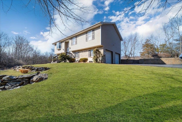 view of side of home featuring a lawn, an attached garage, and driveway