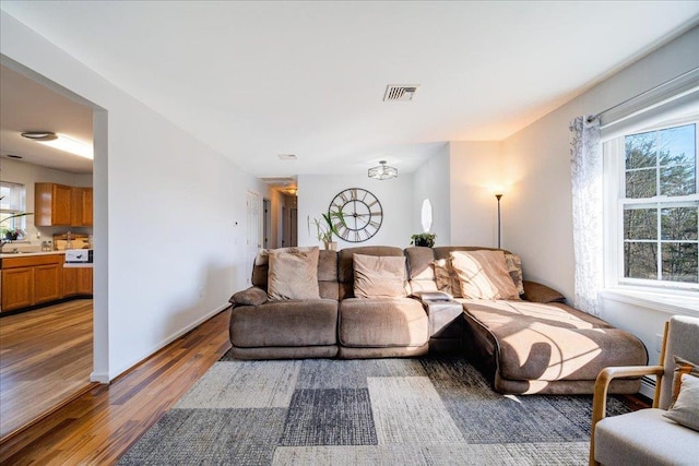 living room featuring a wealth of natural light, visible vents, baseboards, and light wood-style flooring