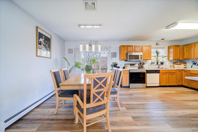 dining room with baseboard heating, a healthy amount of sunlight, light wood-type flooring, and visible vents