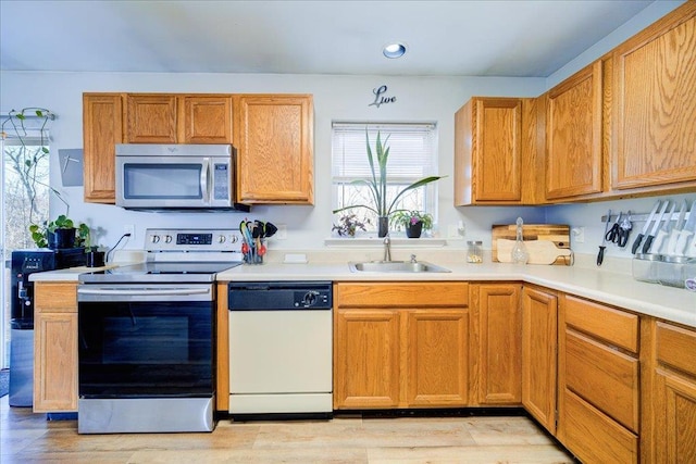 kitchen featuring a sink, stainless steel appliances, brown cabinetry, and light countertops