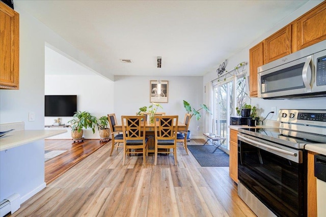 kitchen with light wood finished floors, baseboard heating, appliances with stainless steel finishes, and light countertops