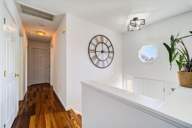 hallway with visible vents, attic access, baseboards, and wood finished floors