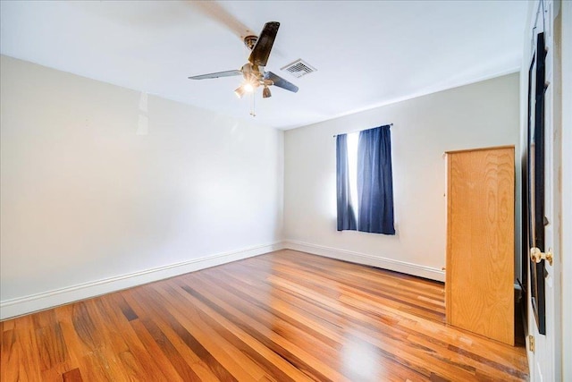 empty room with visible vents, a ceiling fan, baseboards, and wood finished floors