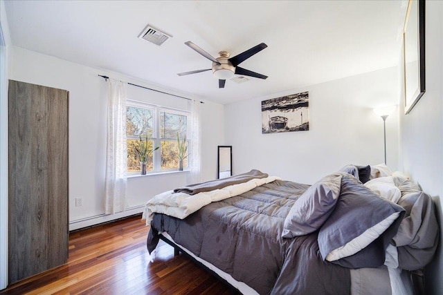 bedroom with wood-type flooring, a ceiling fan, visible vents, and baseboard heating