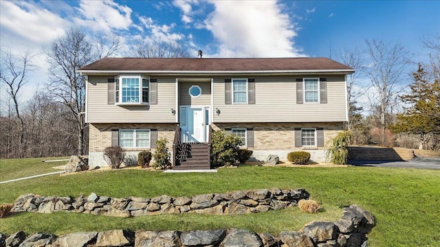 raised ranch with brick siding and a front yard