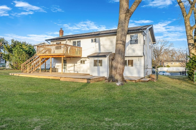 rear view of property featuring a deck, stairs, a lawn, and a chimney