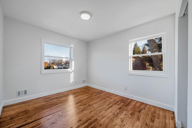 spare room featuring visible vents, a healthy amount of sunlight, and wood finished floors