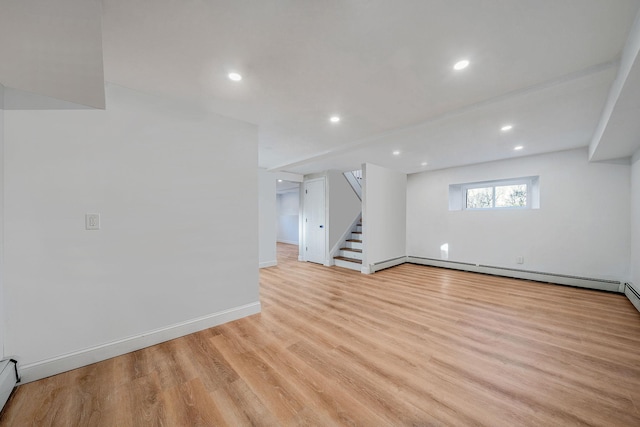 basement with recessed lighting, light wood-style floors, a baseboard radiator, baseboards, and stairs