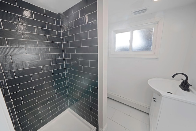 bathroom with vanity, baseboards, visible vents, and a tile shower