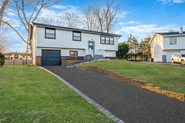 raised ranch featuring a front yard, fence, a garage, and driveway