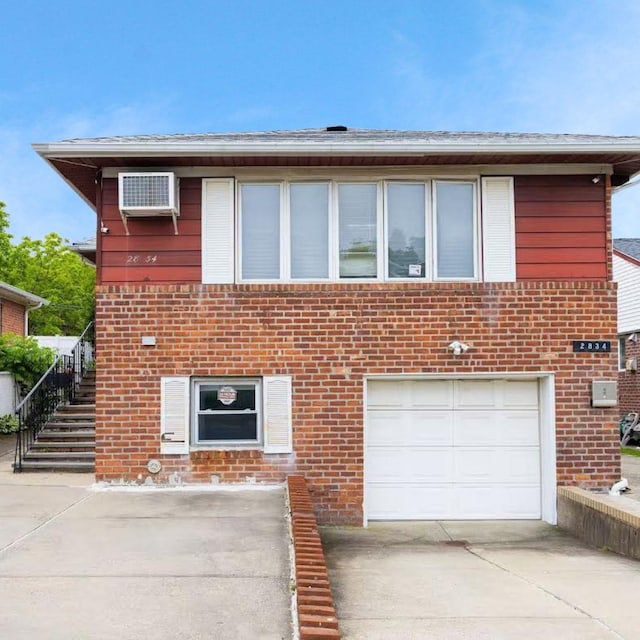 28-34 Corporal Kennedy St, Flushing, NY 11360 - view of front of house with an attached garage, brick siding, and driveway