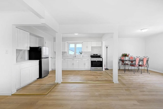 28-34 Corporal Kennedy St, Flushing, NY 11360 - kitchen featuring appliances with stainless steel finishes, light countertops, white cabinets, tasteful backsplash, and light wood-type flooring