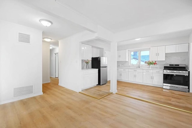 28-34 Corporal Kennedy St, Flushing, NY 11360 - kitchen with appliances with stainless steel finishes, light countertops, light wood-style floors, white cabinets, and a sink