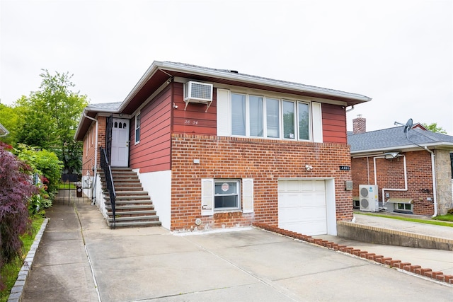 28-34 Corporal Kennedy St, Flushing, NY 11360 - view of front facade featuring concrete driveway, a garage, brick siding, and a wall mounted air conditioner