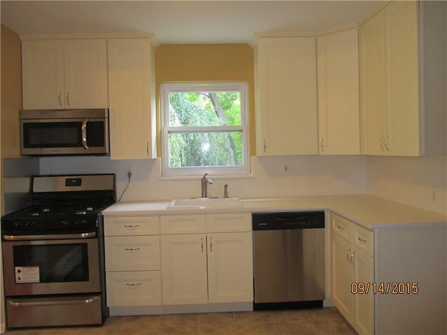 kitchen featuring white cabinetry, stainless steel appliances, light countertops, and a sink