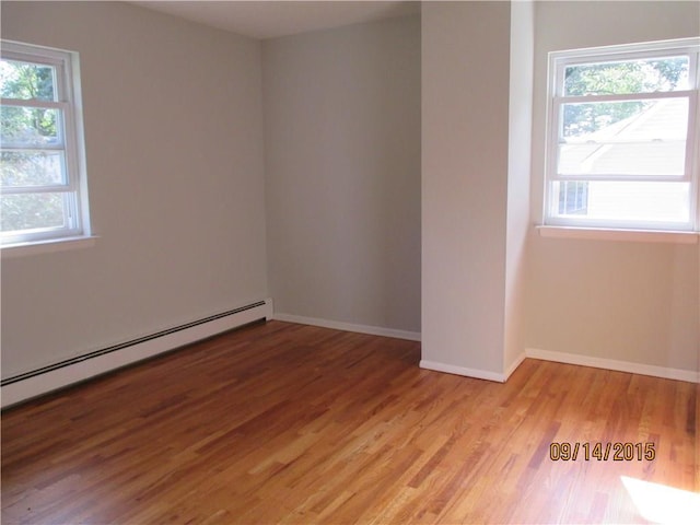 spare room featuring light wood-style flooring, baseboards, and a baseboard radiator