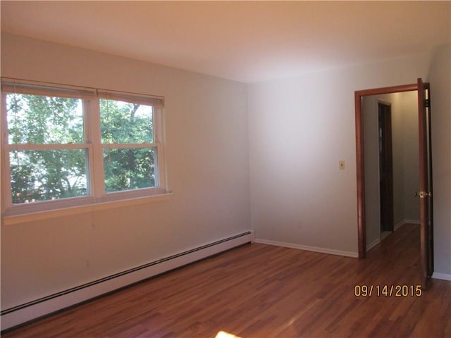 spare room with wood finished floors, baseboards, and a baseboard radiator