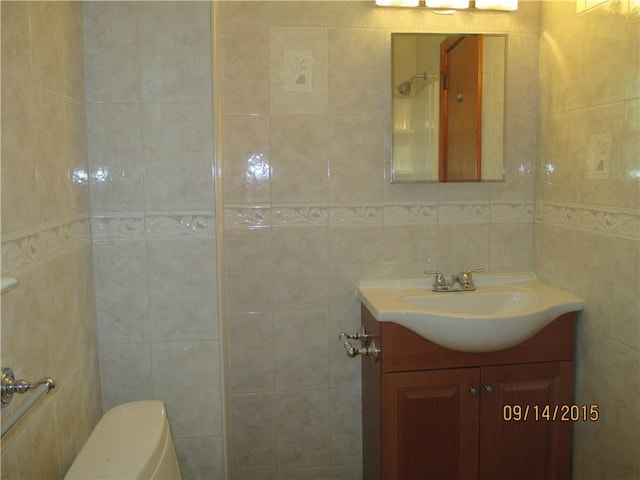 bathroom with toilet, tile walls, and vanity