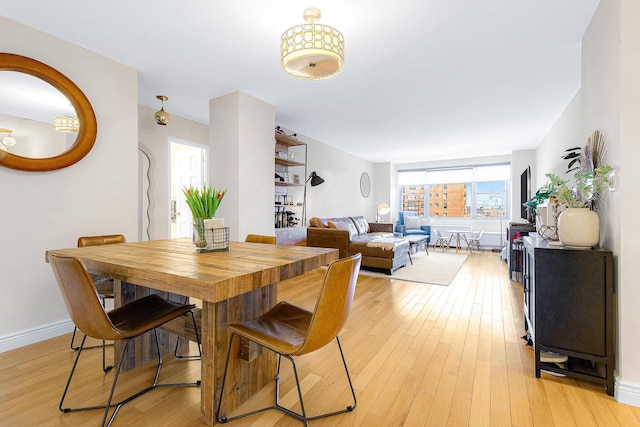 dining room featuring light wood-style flooring and baseboards