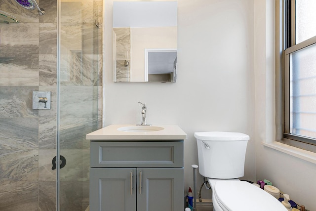 full bath featuring tiled shower, toilet, and vanity