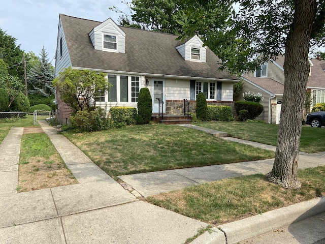 new england style home with a gate, roof with shingles, a front yard, and fence