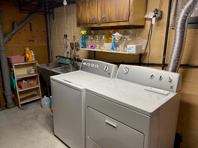 washroom with a sink, cabinet space, and separate washer and dryer