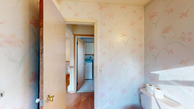 bathroom featuring wallpapered walls, washer / dryer, toilet, and wood finished floors