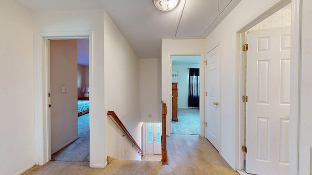 hall with an upstairs landing, light carpet, and attic access