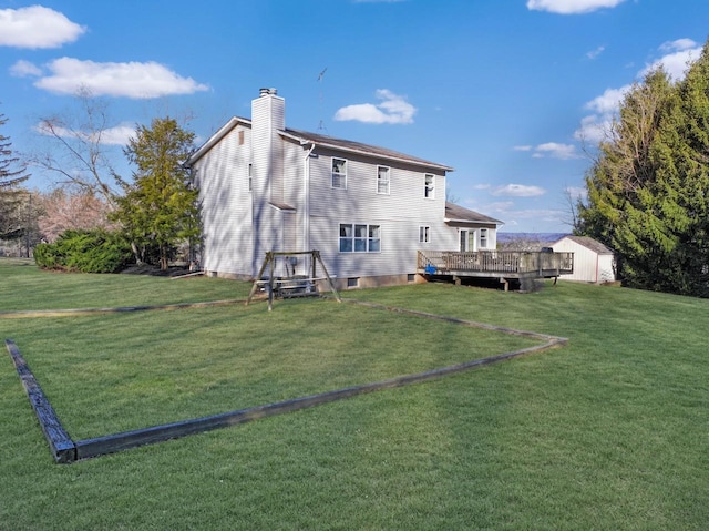 rear view of house featuring an outbuilding, a yard, a chimney, a deck, and a storage shed