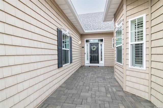 entrance to property featuring roof with shingles